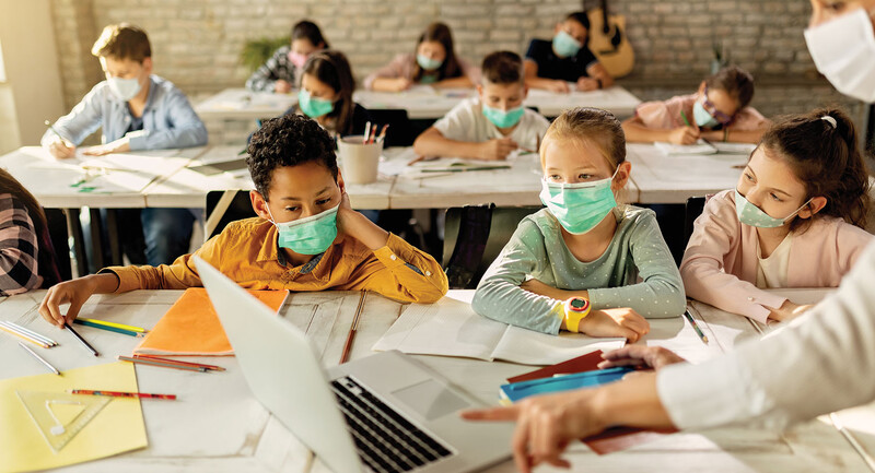 Photo of young students in a classroom wearing masks