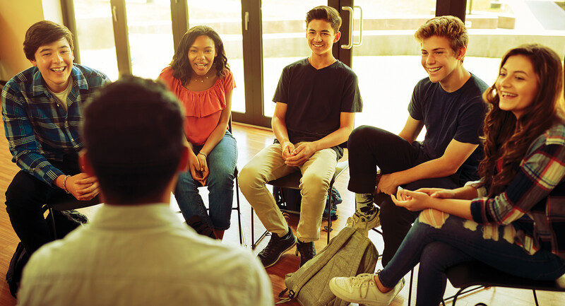 Photo of students seated in a circle listening and talking