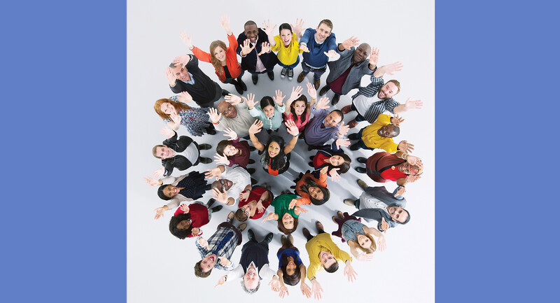 An above shot of people standing in a circle smiling and waving to the camera