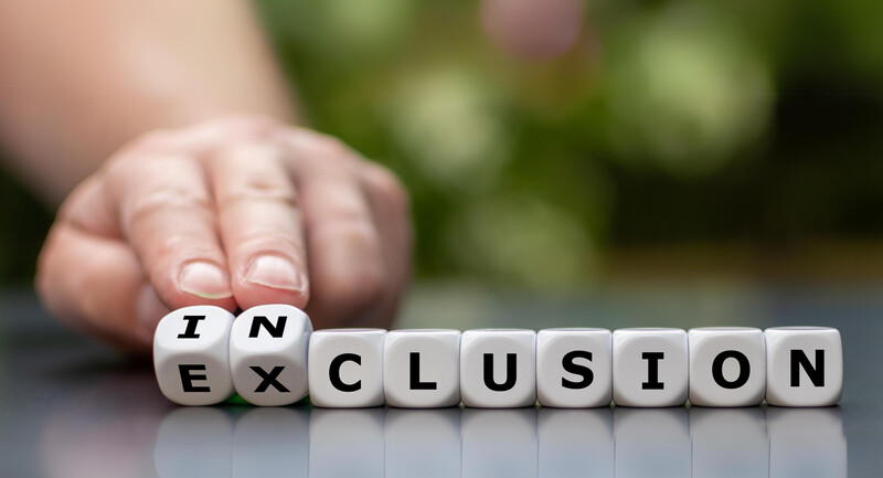 Photo of hand turning two dice to change the word exclusion to inclusion