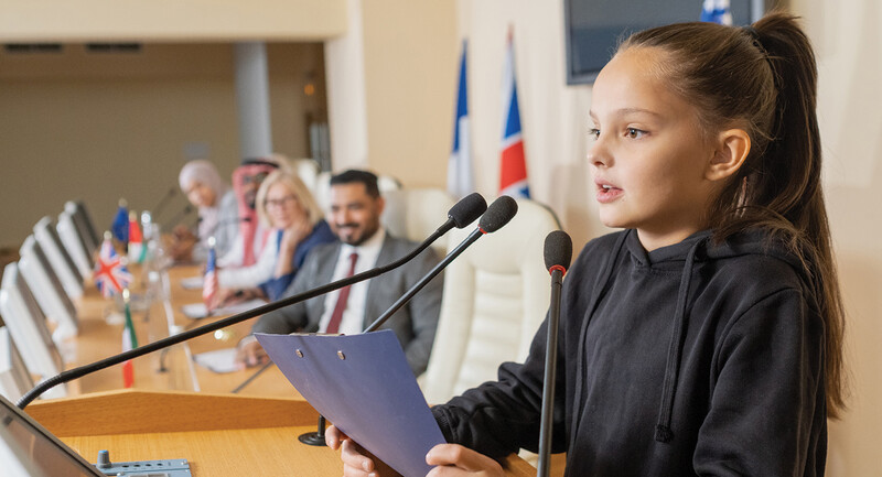 Photo of a young female student speaking at a podium