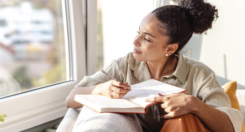 Photo of a young woman of color writing in a journal